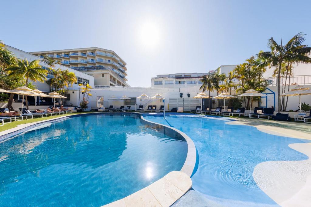 a large swimming pool with chairs and umbrellas at Ramada Resort by Wyndham Shoal Bay in Shoal Bay