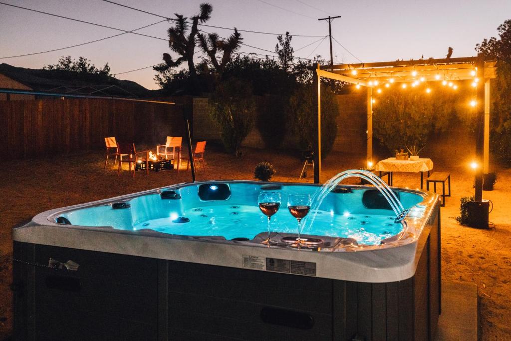 a hot tub in a yard with two glasses of wine at Minutes to JT National Park, Hot Tub & Game Room in Joshua Tree