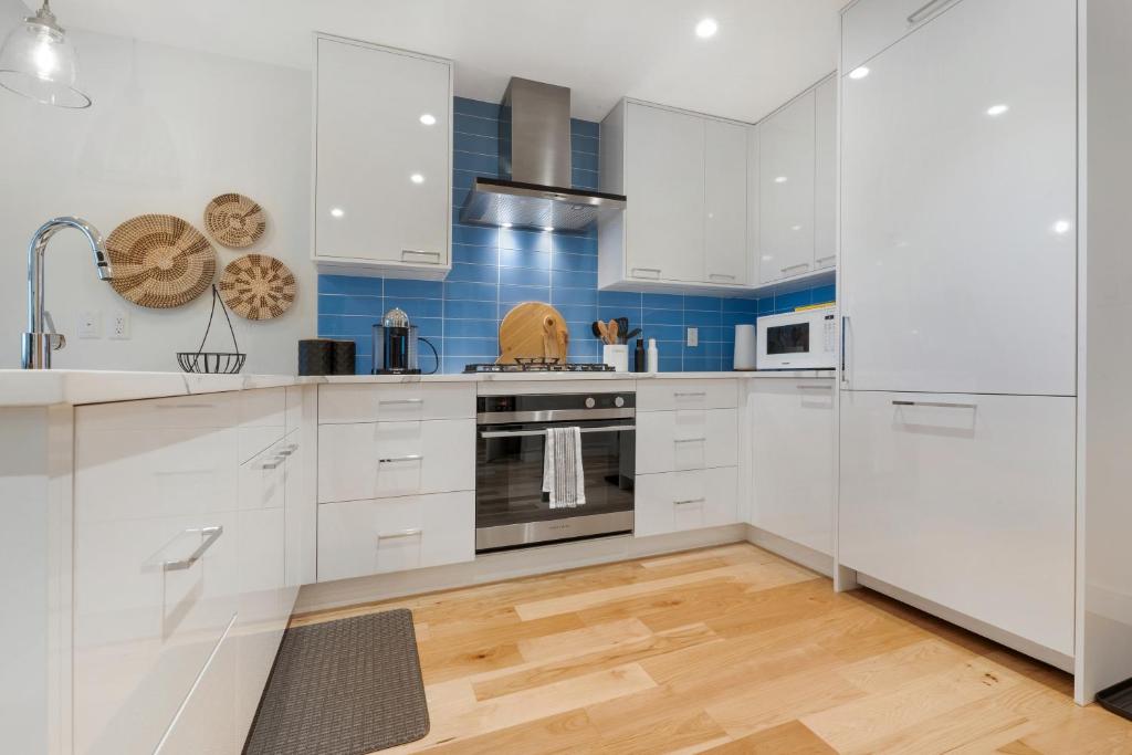 una cocina con armarios blancos y azulejos azules en West Bay Bliss, en Victoria