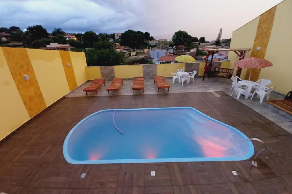 - une piscine bleue sur une terrasse avec des tables et des chaises dans l'établissement Chácara Helenna Colonetti, à Lindóia