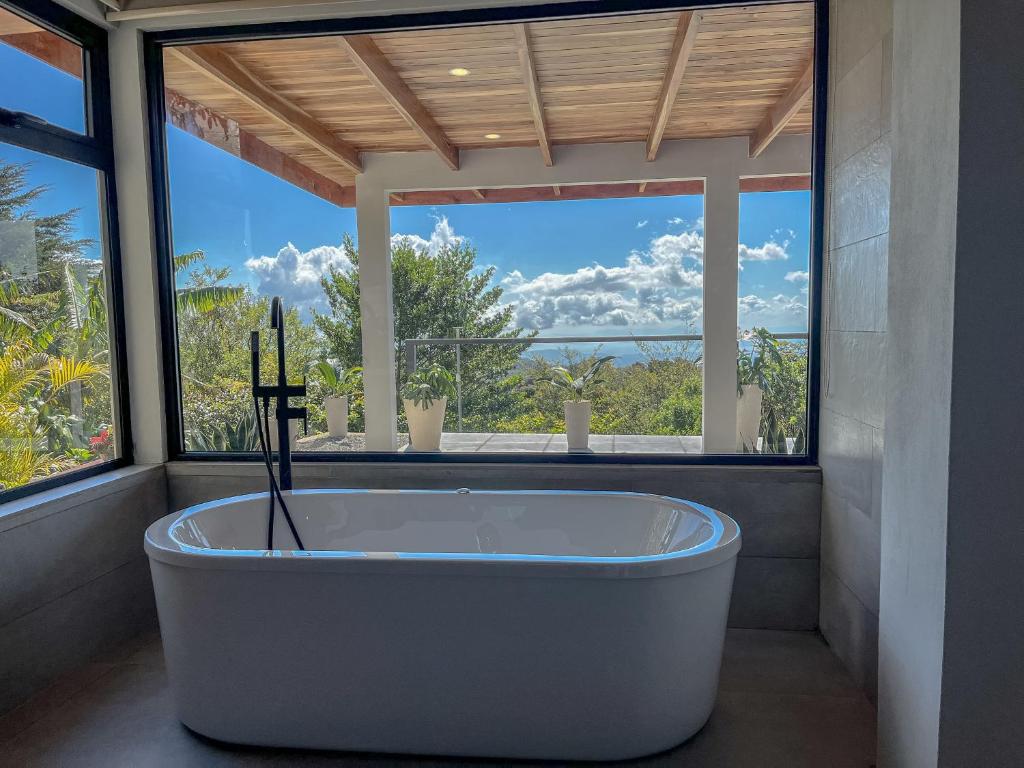 a bath tub in a bathroom with a large window at Flower’s Paradise Monteverde in Monteverde Costa Rica