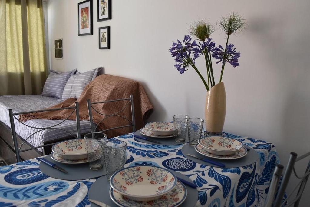 una mesa con platos y un jarrón con flores púrpuras en Departamento nuevo en Condominio Portezuelo, cerca de todo en Salta