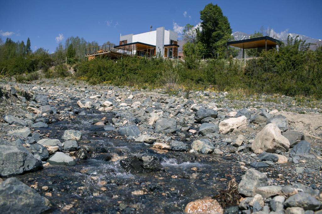 a river with rocks in front of a house at Casa de Montaña - Hunuc Huar in Potrerillos