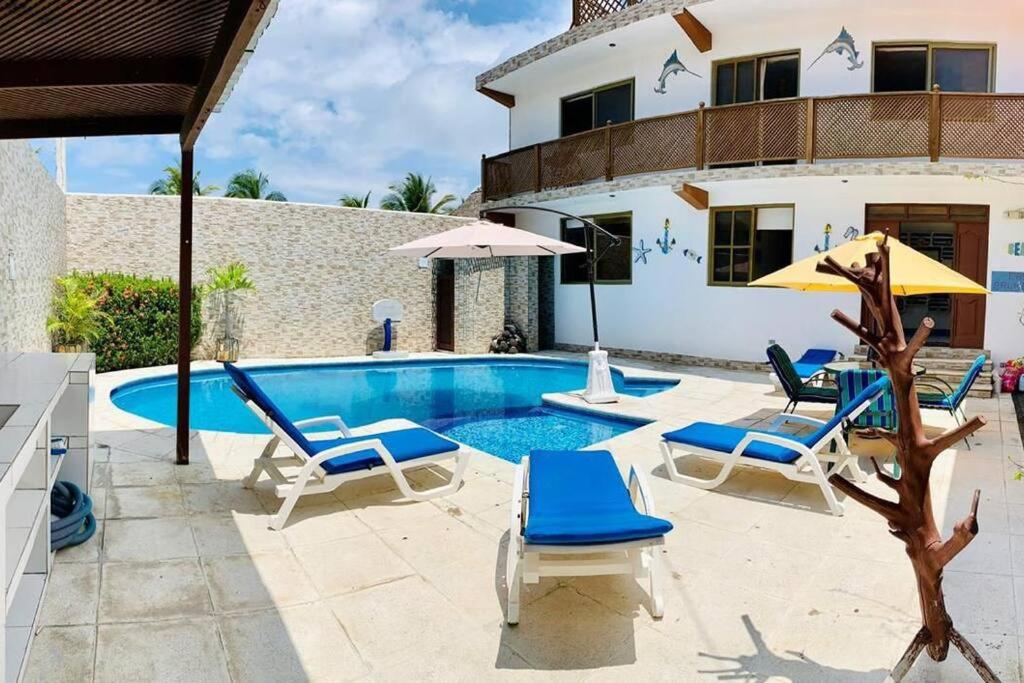 a pool with chairs and umbrellas next to a house at Casa en el puerto frente al mar! in San José de Guatemala