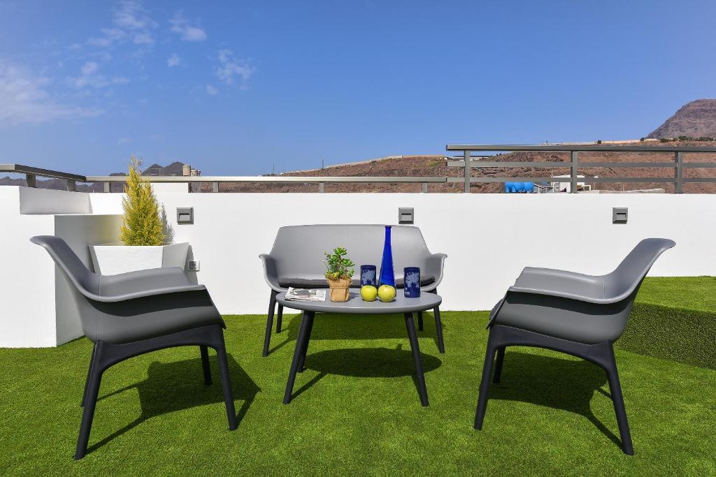 a patio with two chairs and a table on grass at Apartamento Starlight La Aldea I in San Nicolás