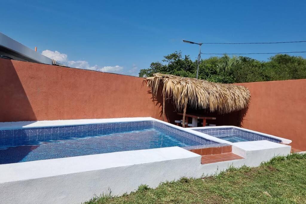 una piscina junto a un edificio con techo de paja en Casa de playa Tortugas Place., en Escuintla