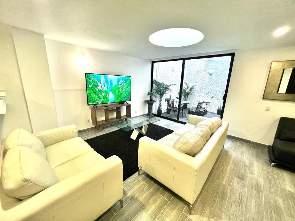 uma sala de estar com 2 sofás brancos e uma televisão de ecrã plano em C22-2 Hermoso departamento con Terraza em Cidade do México