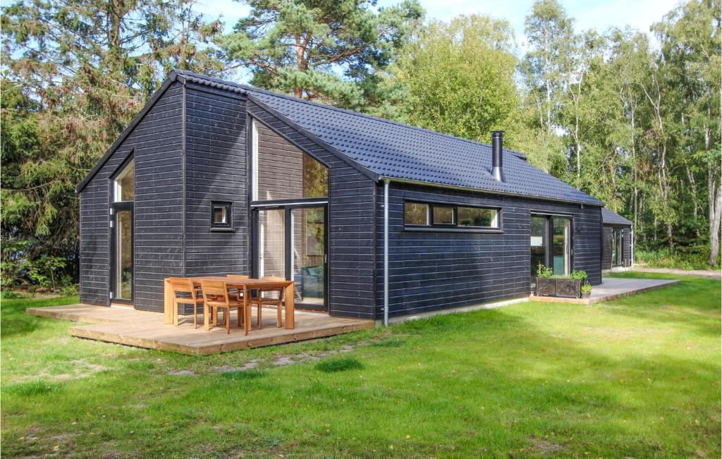 a black house with a wooden table in a yard at Lovely Home In Samsø With Wifi in Nordby