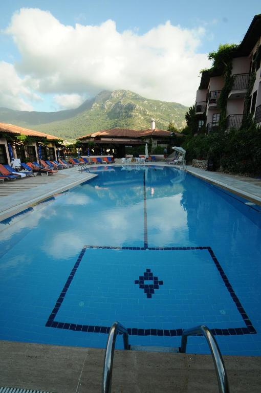 a large blue swimming pool with a mountain in the background at Hisar Holiday Club in Oludeniz