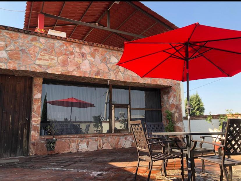 a table and chairs with red umbrellas on a patio at Bonito departamento y Terrazas in Cholula
