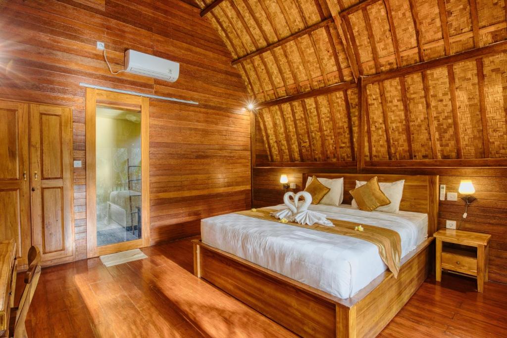 ein Schlafzimmer mit einem Bett in einem Holzzimmer in der Unterkunft Puri Yalus Bungalow in Nusa Penida