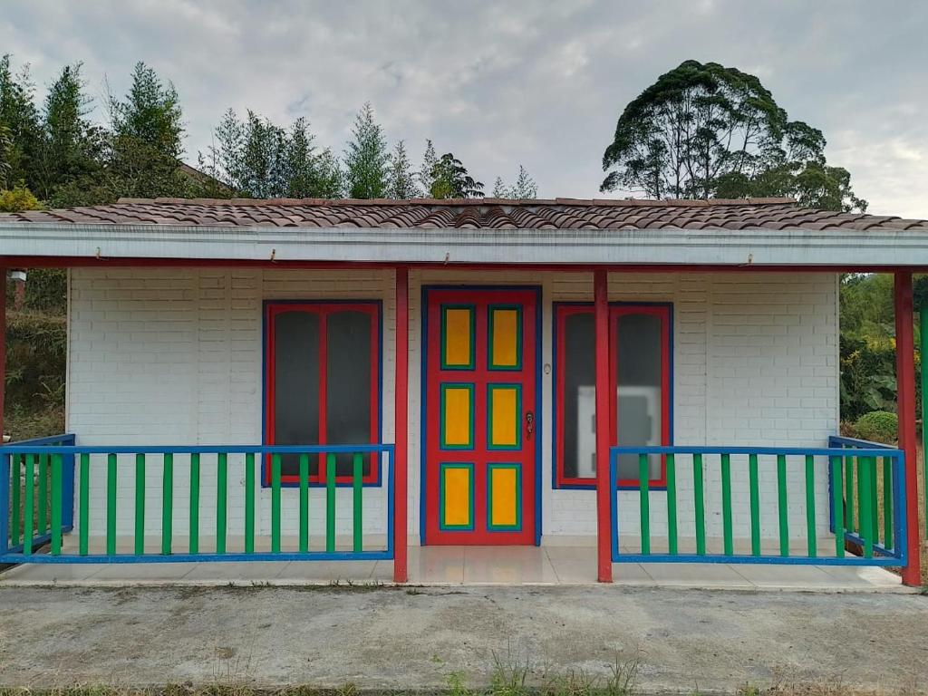una pequeña casa con puertas coloridas en la parte delantera en Acogedoras - Cabañas Villa Paty, en Santa Rosa de Cabal