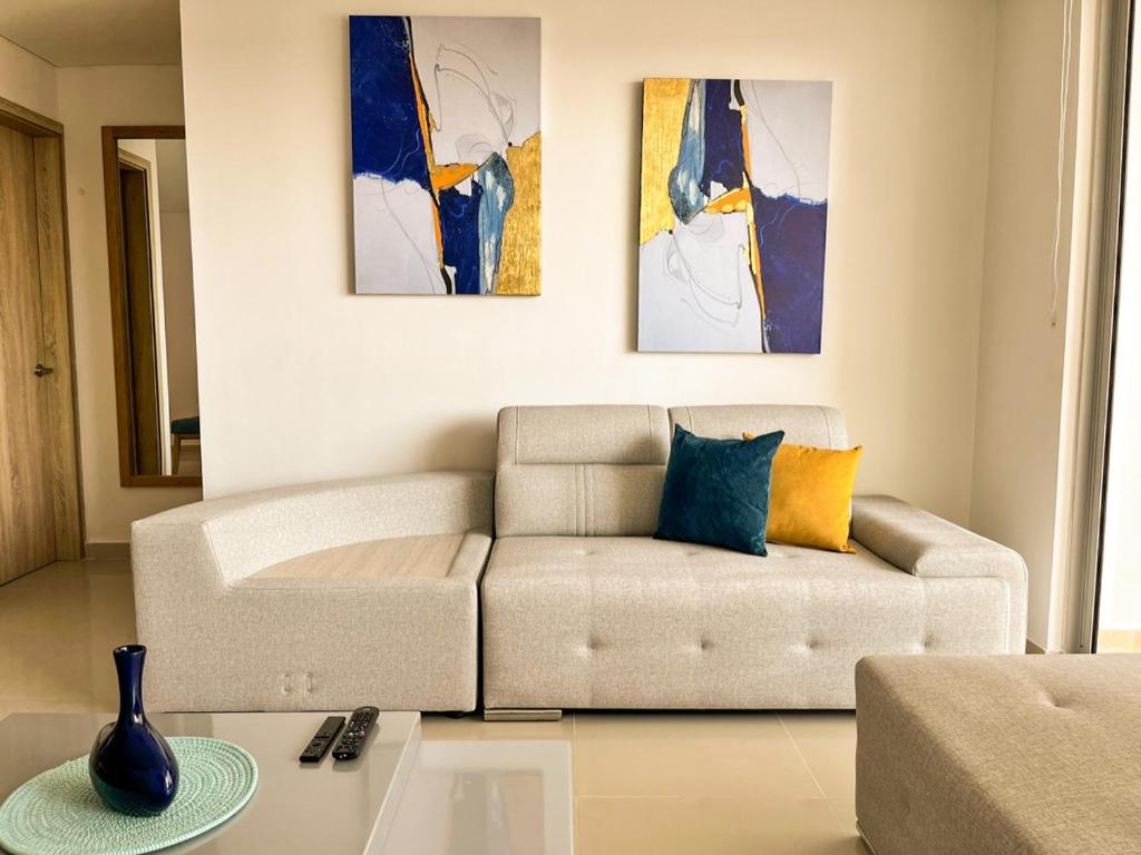 sala de estar con sofá y pinturas en la pared en Exclusivo Apartamento Frente Al Mar En Cartagena, en Cartagena de Indias