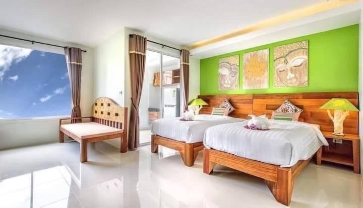 una camera con due letti e una parete verde di The Cheetar Hotel a Amphoe Kathu