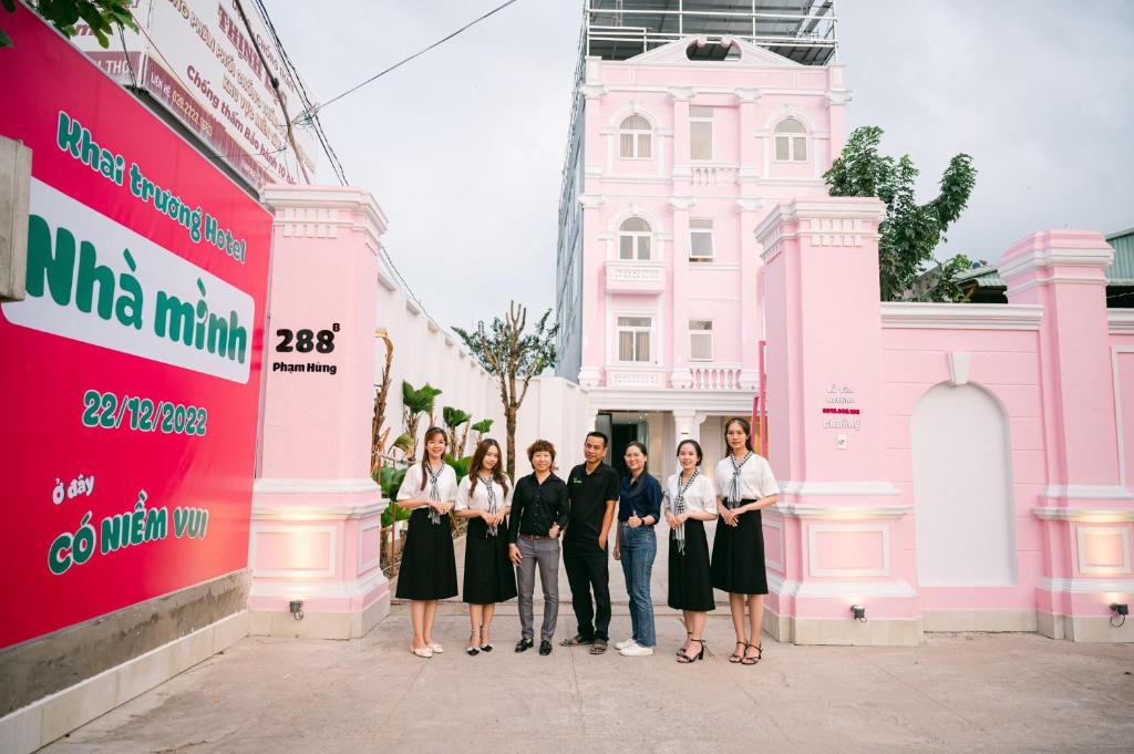 Cái RăngにあるKhách Sạn Nhà Mìnhのピンクの建物の前に立つ集団