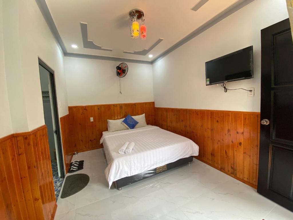 Schlafzimmer mit einem Bett und einem Flachbild-TV in der Unterkunft Nhà nghỉ Cát Đằng Hồ Tràm in Hồ Tràm