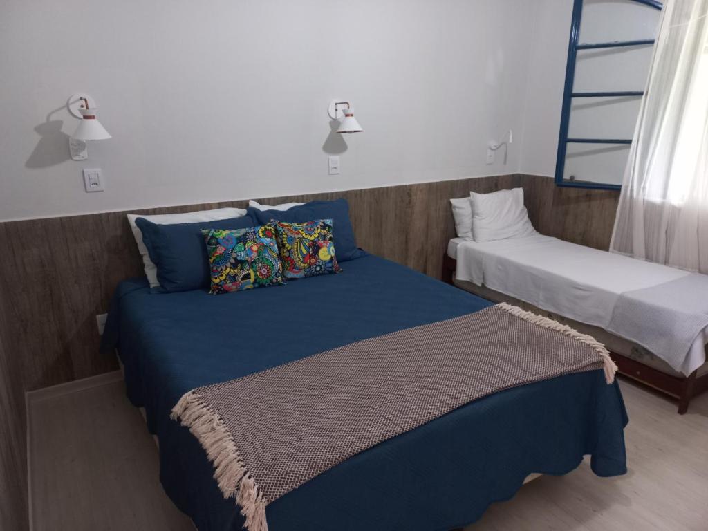 1 Schlafzimmer mit 2 Betten und blauer Bettwäsche in der Unterkunft Recanto Caminho das Águas in Caxambu