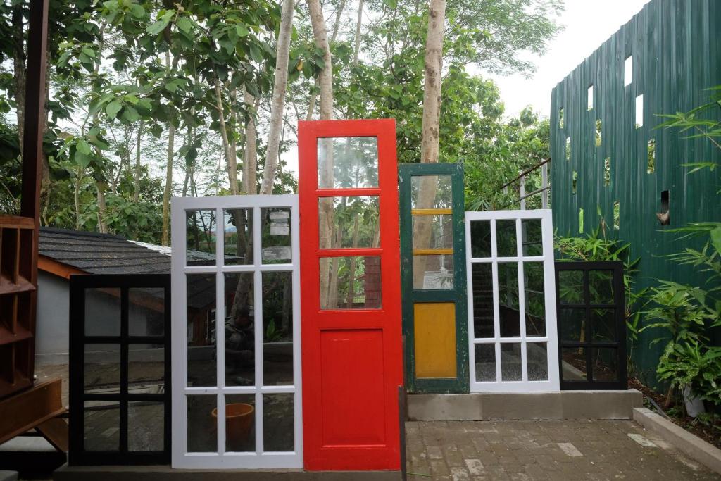 una puerta roja junto a dos puertas blancas en Urbanview Villa Lukulo Kebumen by RedDoorz, en Kebumen