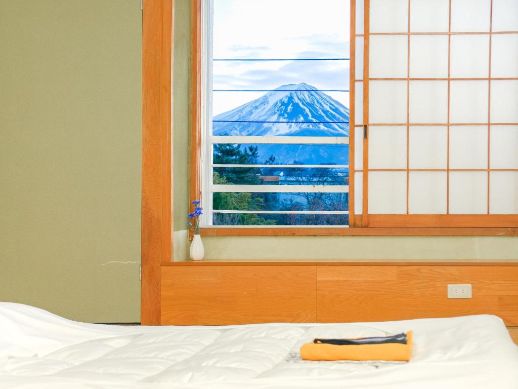 a bed with a window with a view of a mountain at 芙蓉山居煙霞ー元富士の屋旅館ー in Fujikawaguchiko