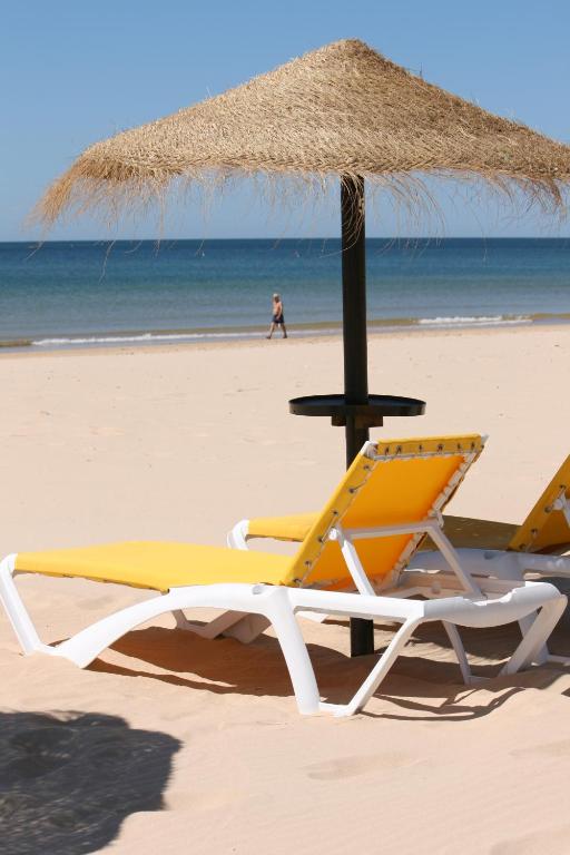 dos sillas y una sombrilla en una playa en Casa de férias in RETUR, praia do Cabeço, Algarve, en Castro Marim
