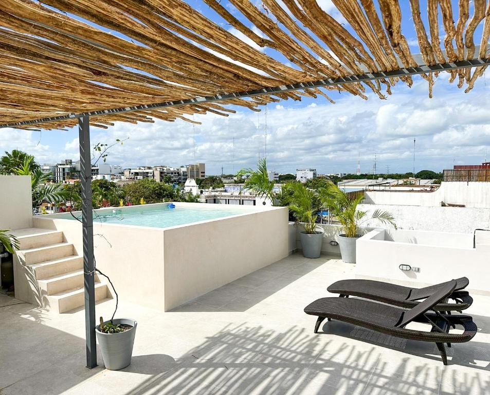 a patio with chairs and a swimming pool on a roof at Balam Suites in Playa del Carmen