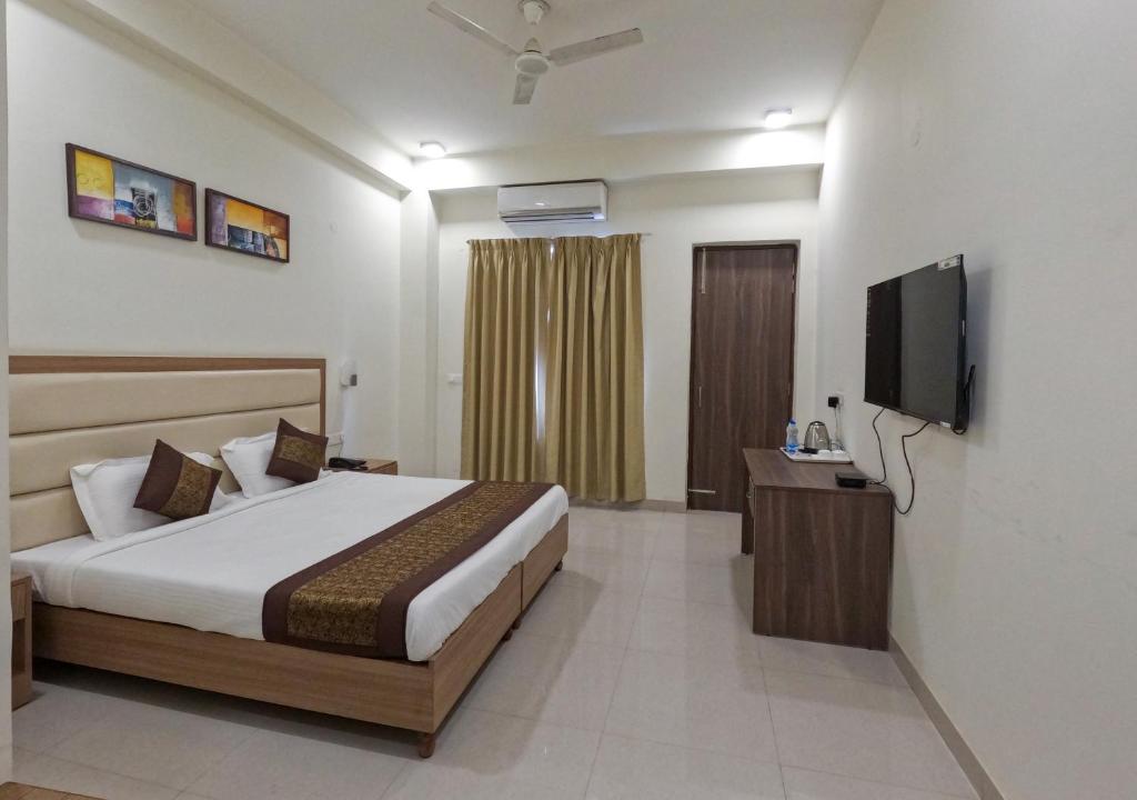 a bedroom with a bed and a flat screen tv at Hotel The Luxem - Behind Ibis Hotel Gurugram in Gurgaon