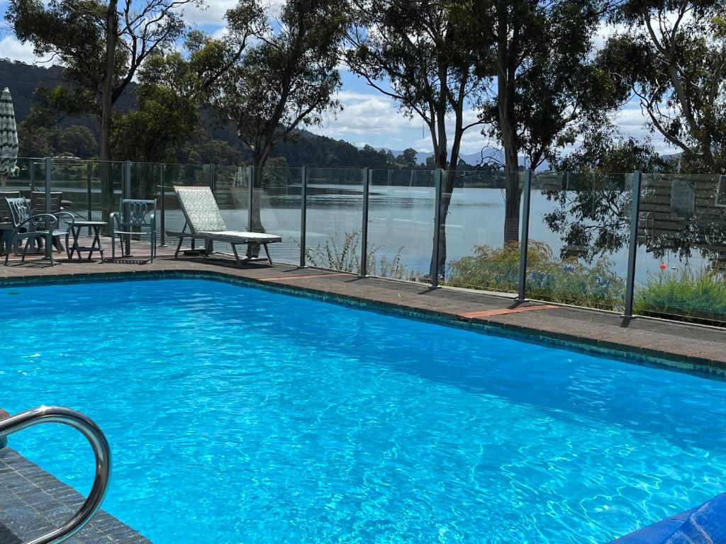 a large blue swimming pool with a view of a lake at Anchorage Waterfront Retreat in Castle Forbes Bay