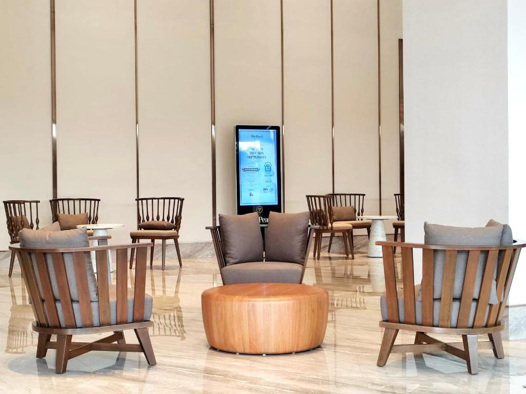 A bright hotel lounge with lounge chairs, small tables and a central digital display.
