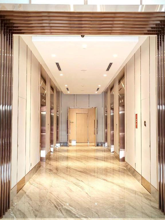 A polished hotel corridor framed by dark wood slats and lined with doors.