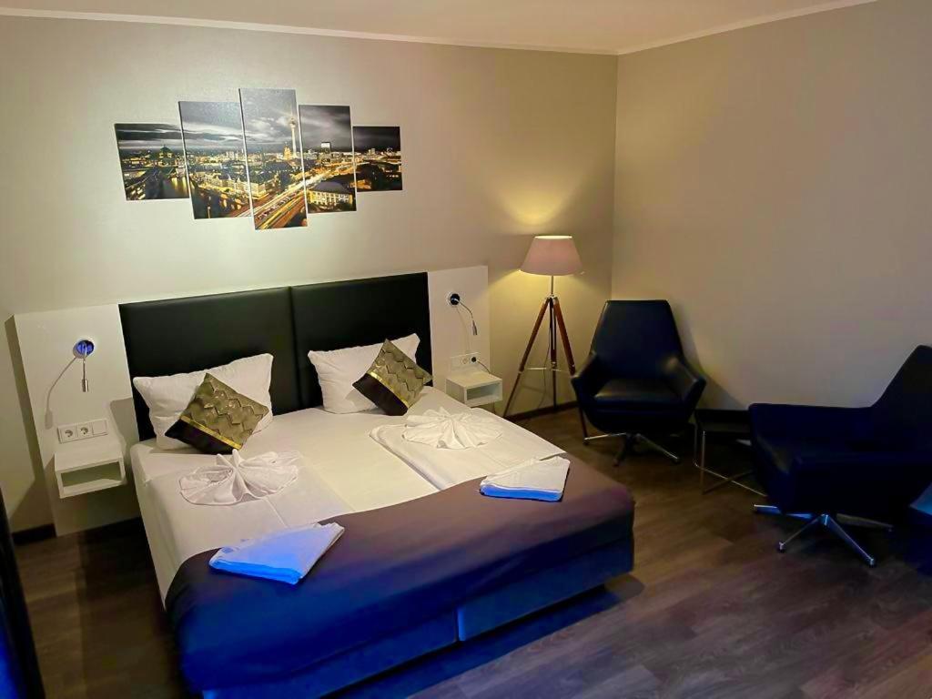 een slaapkamer met een groot bed en 2 stoelen bij ALFA Hotel in Berlijn