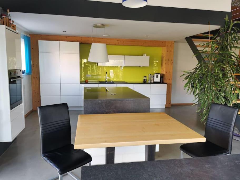 uma cozinha com uma mesa de madeira e cadeiras pretas em Bungalow mit 200 qm Wohnfläche :) em Birgland