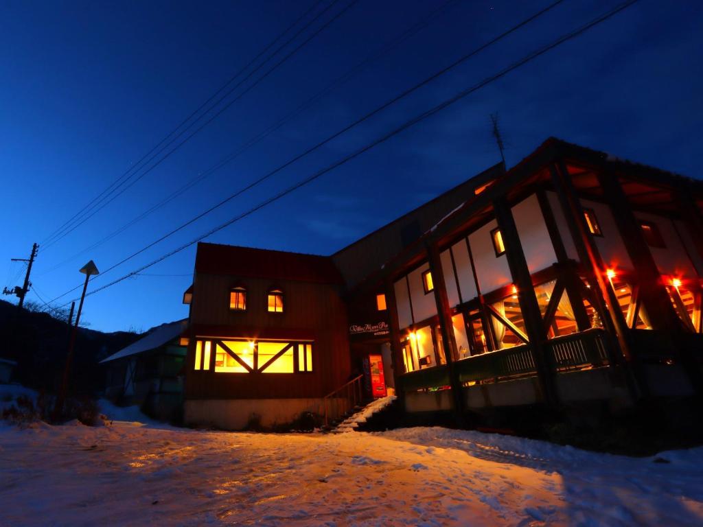 a building with lights on in the snow at night at Villa Monrepos in Myoko