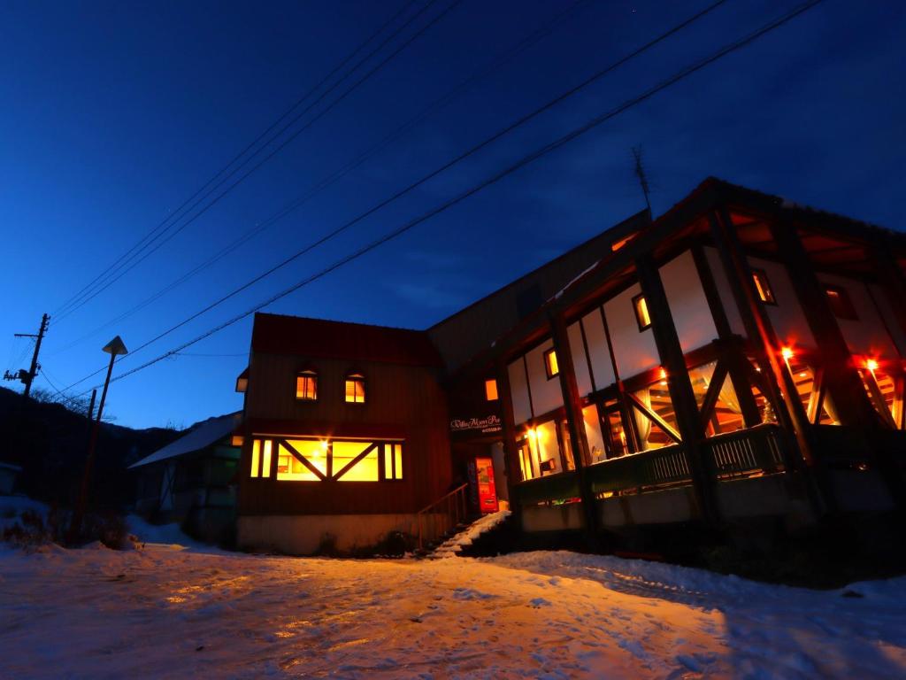 een gebouw met 's nachts lichten in de sneeuw bij Villa Monrepos in Myoko