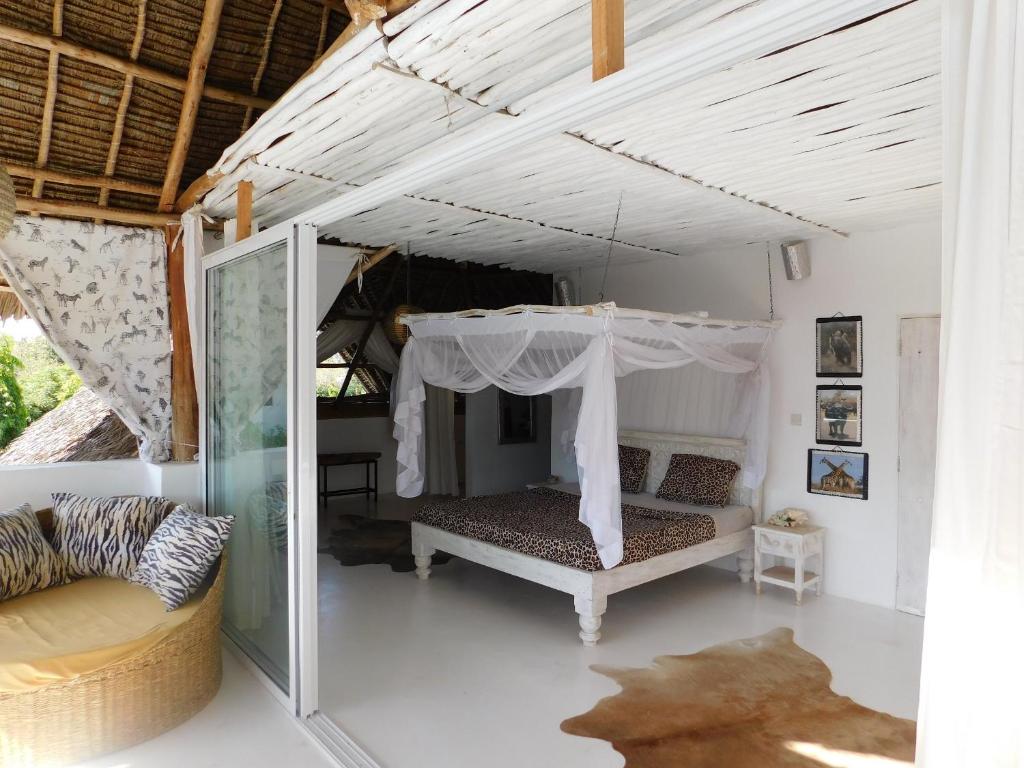 ein Schlafzimmer mit einem Himmelbett und einem Sofa in der Unterkunft Dama Villa in Watamu