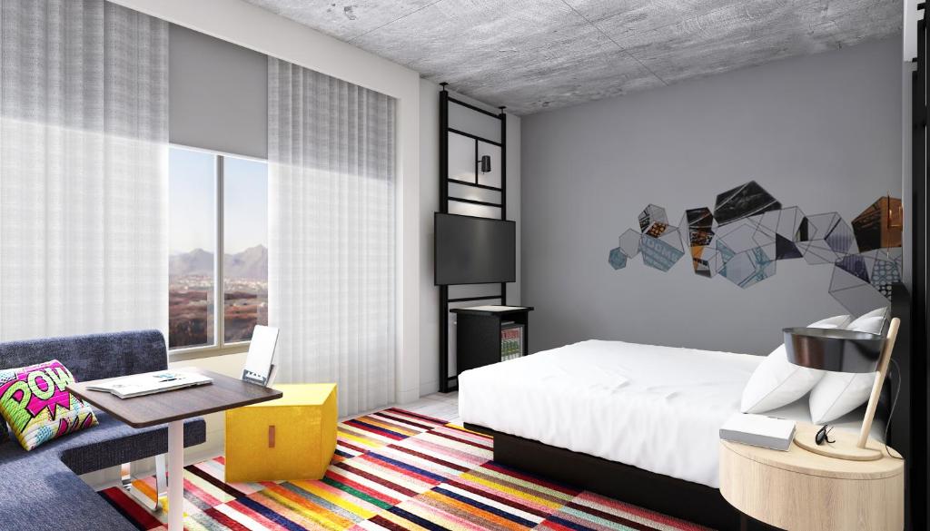 a bedroom with a bed and a table and a couch at Aloft Muscat in Muscat