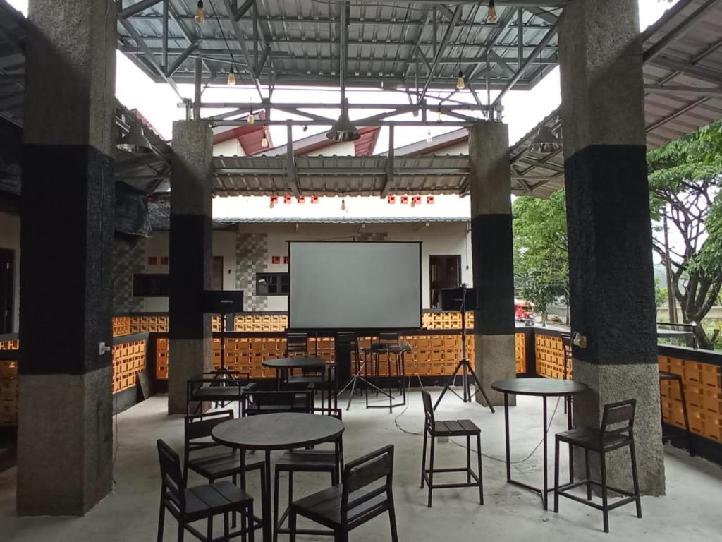 Pondok Wisata Syariah Deporiz في Kadudampit: غرفة كبيرة بها طاولات وكراسي وشاشة