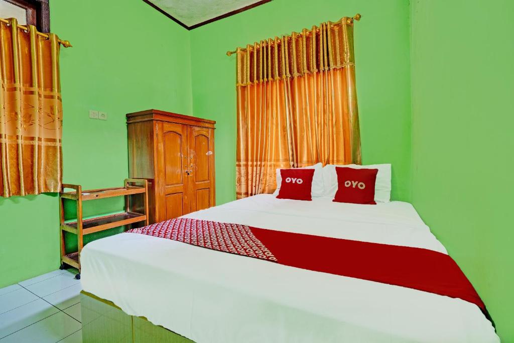 ein Schlafzimmer mit einem Bett mit zwei roten Kissen in der Unterkunft OYO 92062 Pondok Aurel Wahidin in Cirebon