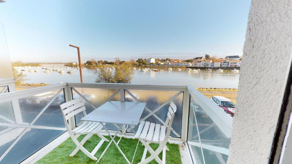 サン・ジル・クロワ・ド・ヴィにあるAppartement Antaresのテーブルと椅子2脚、川の景色を望むバルコニー