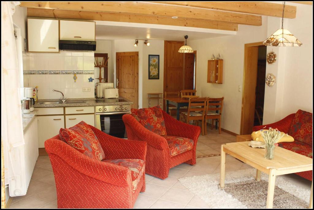 cocina y sala de estar con sillas rojas y mesa en Ferienwohnung Fohrmann, en Haffkrug