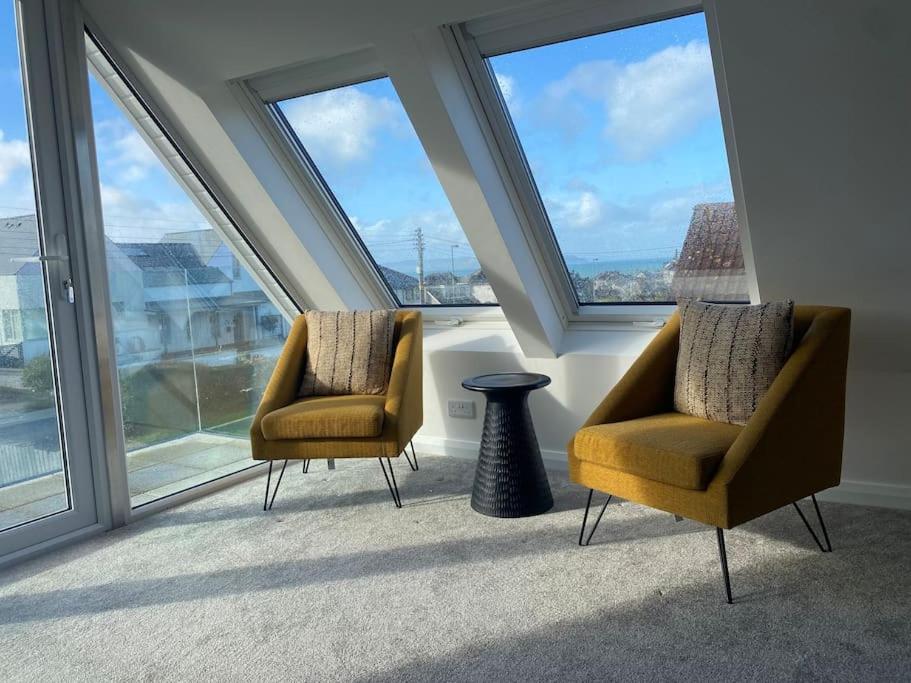 due sedie e un vaso in una stanza con finestre di Modern holiday home with sea view- close to beach a Portstewart