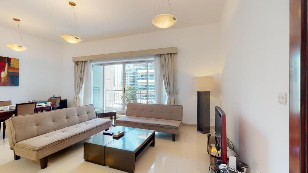 a living room with a couch and a tv at Hometown Apartments - Waterfront 1 Bedroom apartment in Westside Marina in Dubai