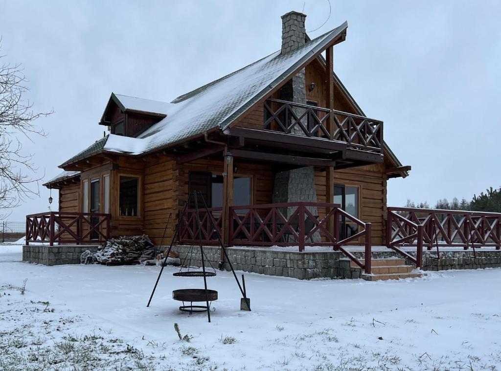 une cabane en rondins dans la neige avec une balançoire dans l'établissement Skrajna Chata Chrzypsko, à Chrzypsko Wielkie