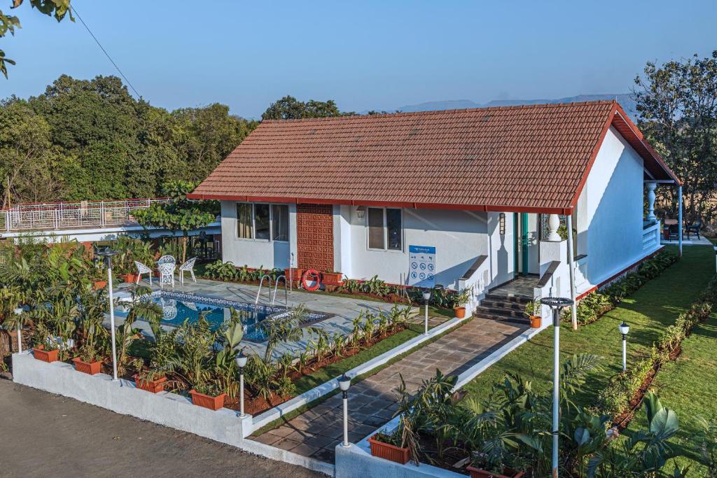 a house with a swimming pool in front of it at SaffronStays Mariposa by the River Rio, Karjat in Karjat