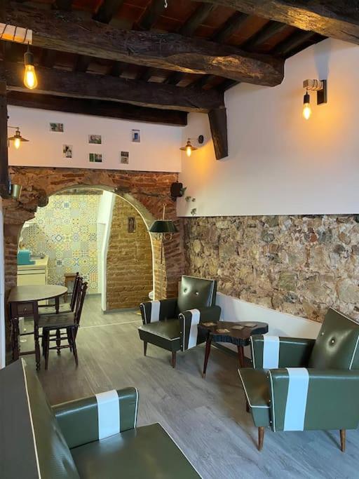 Habitación con sillas, mesas y pared de piedra. en Casa Olivença, en Arraiolos