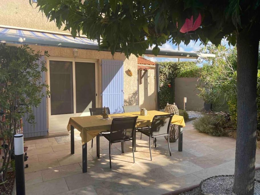 un tavolo giallo e sedie in un patio con un albero di Mazet provencal au coeur des Alpilles La Rêverie a Maussane-les-Alpilles