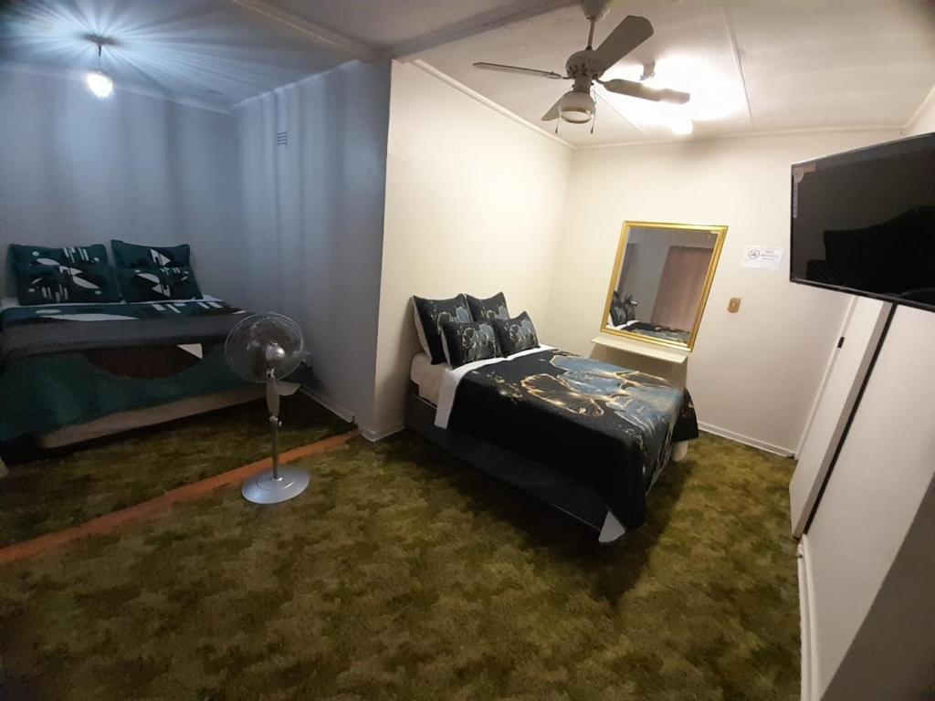 - une chambre avec un lit, un miroir et un ventilateur dans l'établissement Pythons Guest Lodge, à Rustenburg