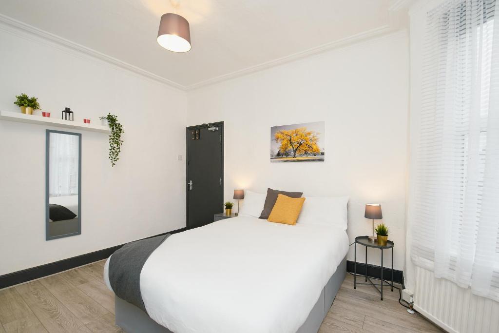 een witte slaapkamer met een groot bed en 2 ramen bij LARGE GROUPS- 5 bed House in Harringay in Londen