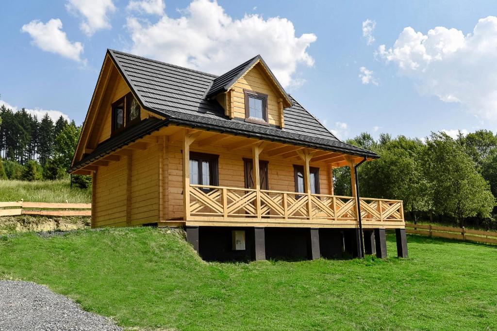 a small wooden house with a balcony on a grass field at Domek w Klisiówkach in Ujsoły