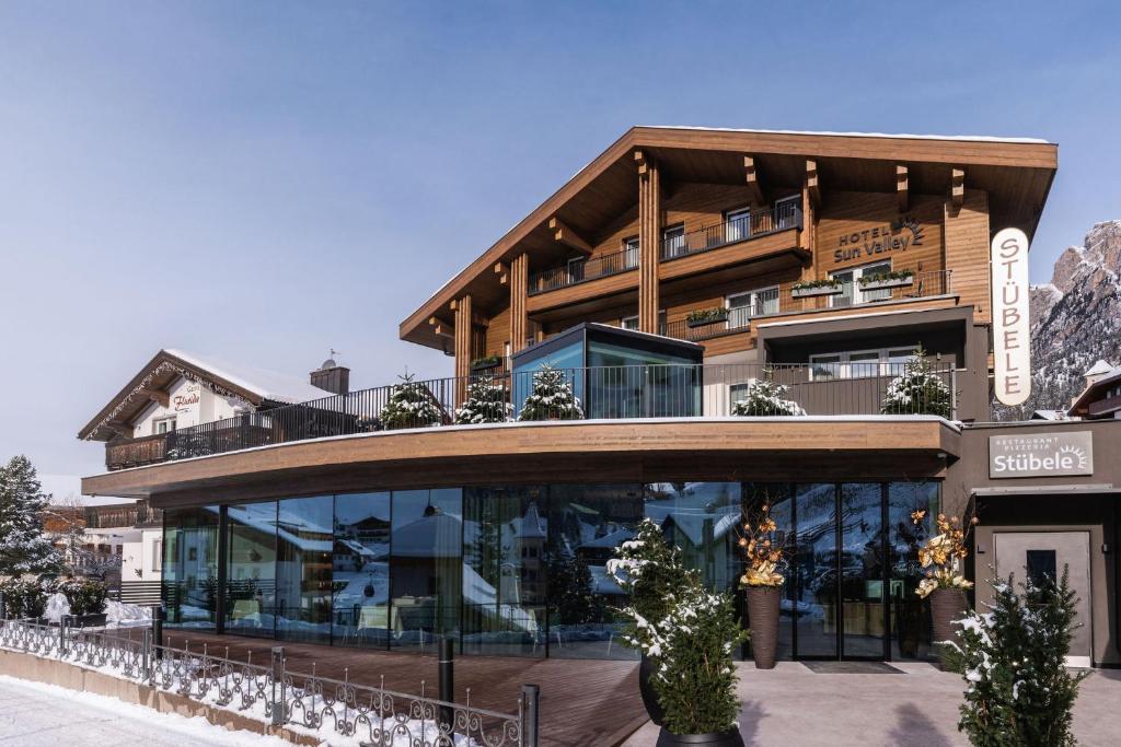 a large building with a balcony on top of it at Hotel Sun Valley in Selva di Val Gardena
