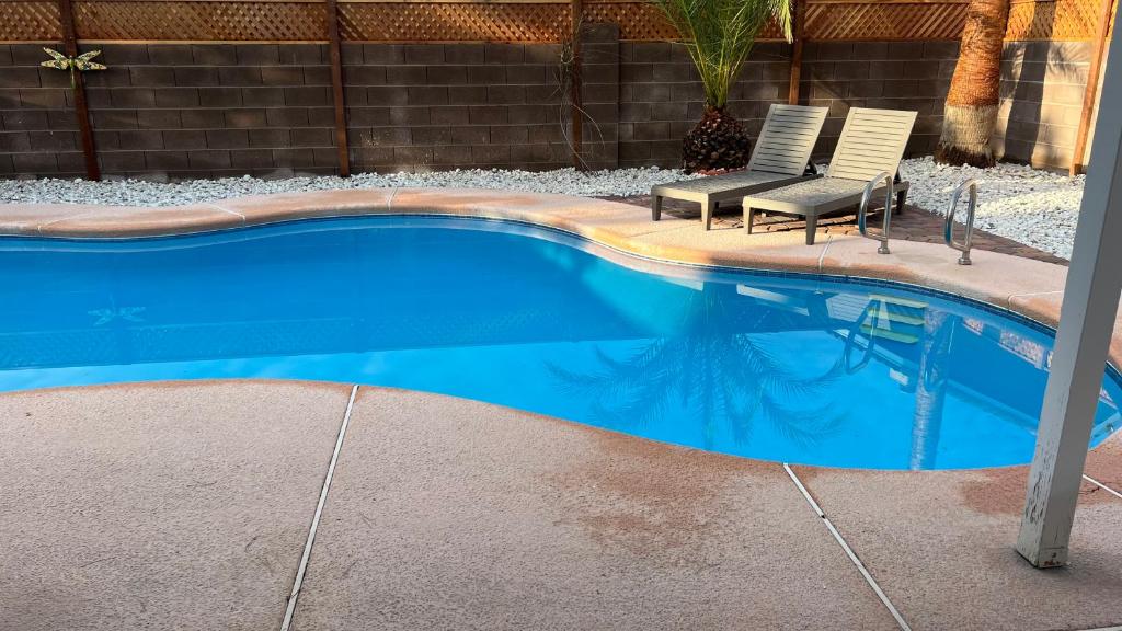 a swimming pool with two chairs next to it at Large Pool & Patio Cozy Single Story Family House in Las Vegas